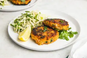 Close-up of golden Thai fish cakes with coriander, spring onions and fresh slaw.