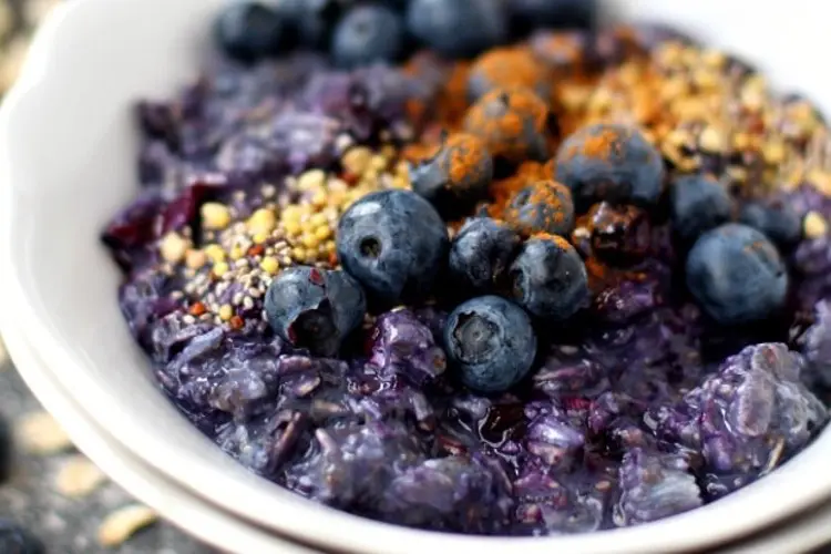 Blueberry Pie overnight oats recipes in a bowl, purple-tinged with fresh blueberries and granola crumble