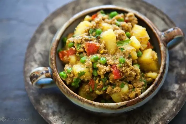 A bowl of curried turkey mince with potatoes, garnished with fresh coriander