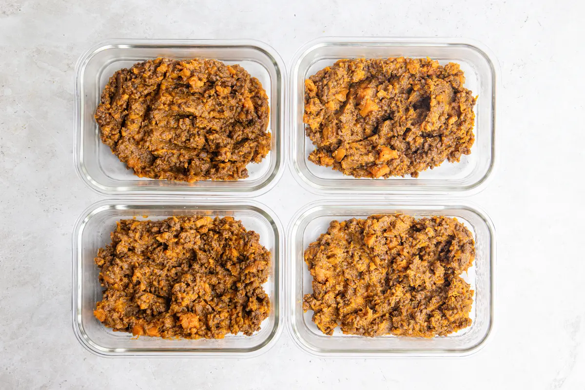 Four glass meal prep containers filled with high-protein sweet potato stovies, ready for batch cooking lunches or dinners.
