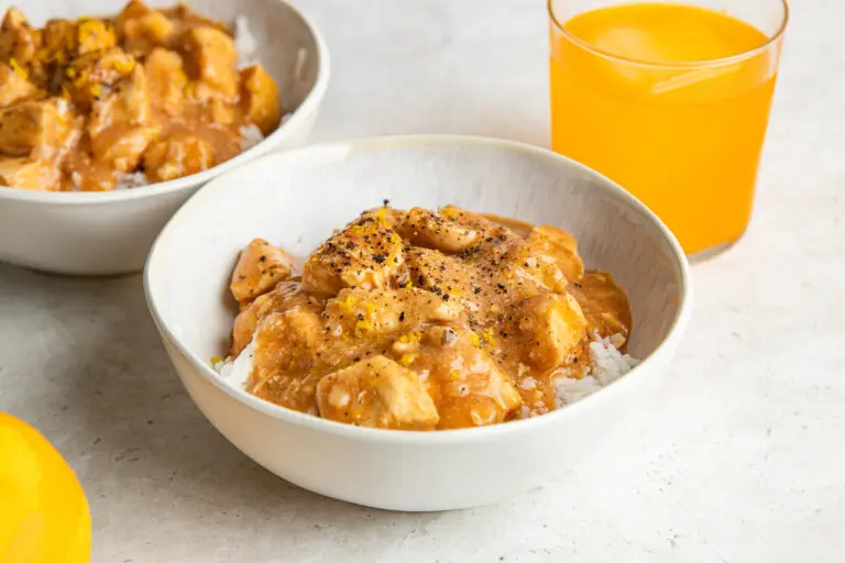 A bowl of Slow Cooker Irn-Bru Chicken served over fluffy white rice, with tender chicken breast coated in the rich orange sauce and finished with orange zest.