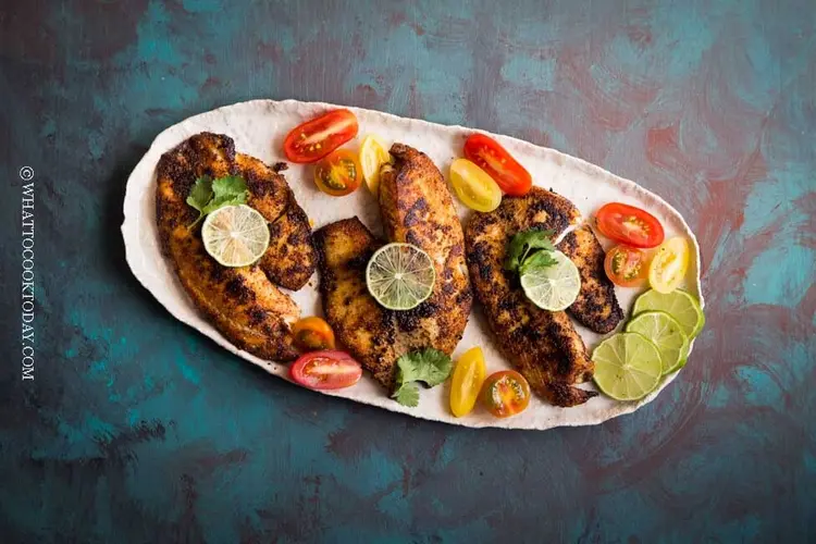 Flaky grilled fish fillets marinated in a spicy Cajun-style barbeque marinade, served with lemon wedges and grilled veg.