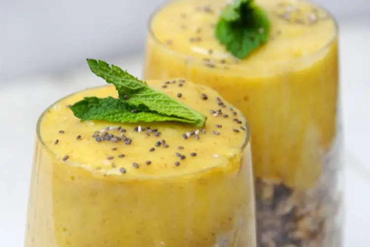 Yellow-orange oats topped with fresh mango cubes and banana slices, with a mint leaf garnish