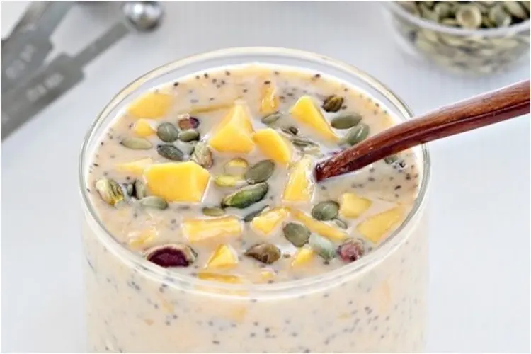 Mango overnight oats recipes served in a glass, bright yellow and topped with mango cubes