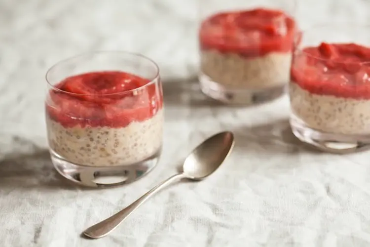 Jar of creamy vanilla chia overnight oats recipes topped with bright pink stewed rhubarb and a sprinkle of chia seed