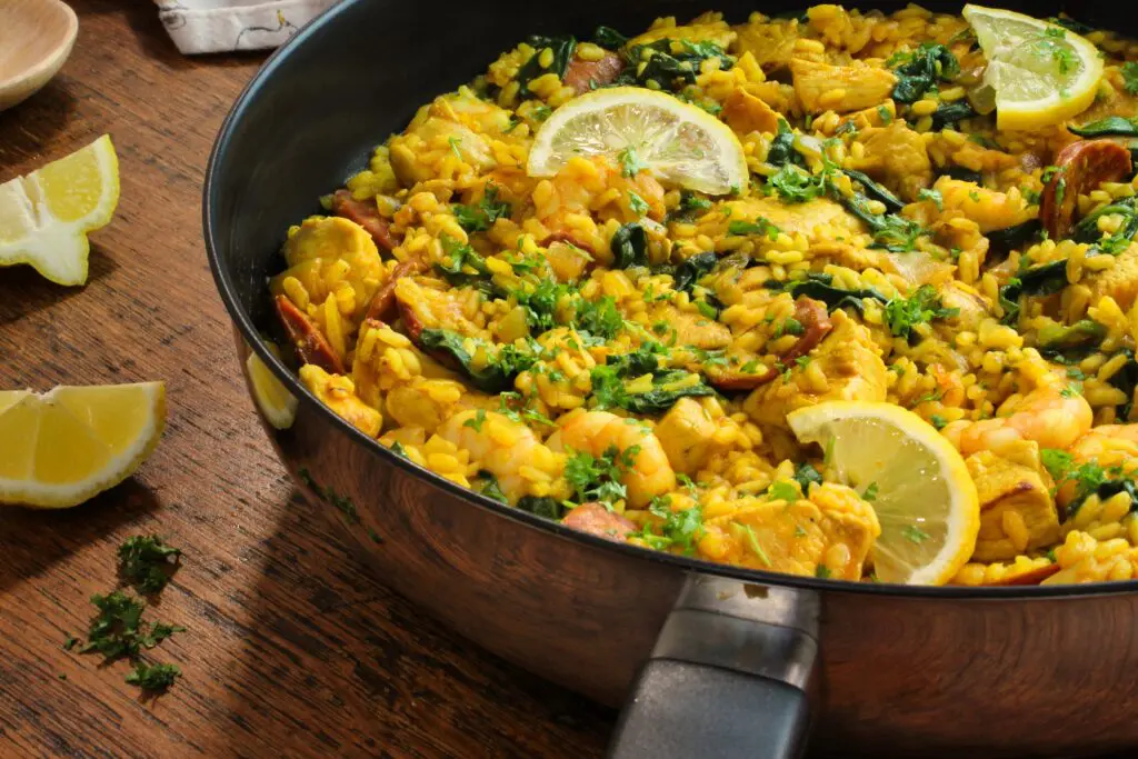 A large pan of sizzling paella, with perfectly cooked rice, crispy chorizo, and succulent chicken, all infused with rich, smoky paprika and turmeric.