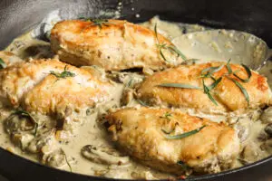 Close-up of Chicken Fricassée with creamy herb sauce and sautéed mushrooms.