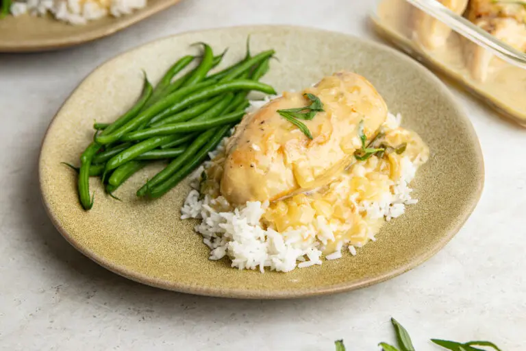 Tender slow cooker tarragon chicken breast in creamy white wine sauce, served with rice and green beans.