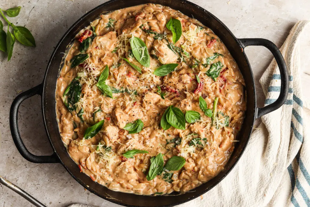Creamy chicken orzo with sun-dried tomatoes and spinach—a one-pan low calorie meal prep dish made for midweek magic.