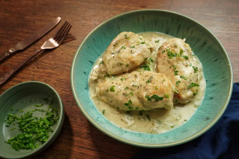 Close-up of creamy tarragon chicken in a bowl, with tender chicken breasts coated in a smooth white wine and tarragon sauce, finished with fresh herbs.