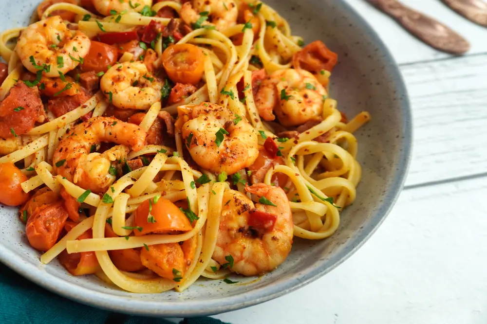 Spicy prawn and chorizo linguini dish with visible herbs and vibrant tomatoes