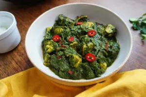 Close-up of Palak Chicken Curry in vibrant green spinach sauce, served in a bowl with red chilli garnish