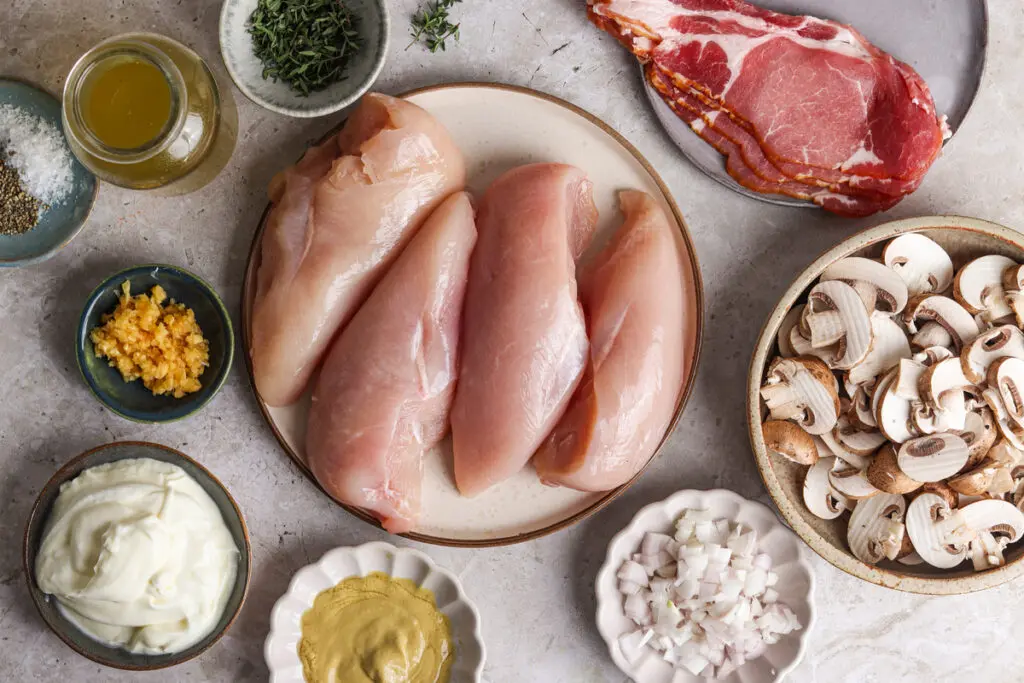 Flat lay of Chicken Supreme ingredients including chicken, bacon, mushrooms, and crème fraîche.