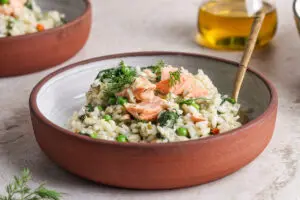 Side angle of salmon risotto showing flaked salmon, wilted spinach, and creamy rice.