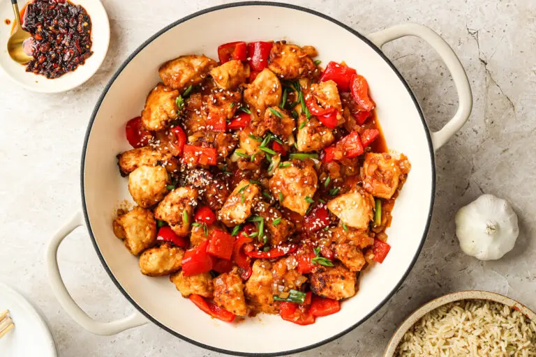 Overhead shot of Manchurian Chicken in casserole dish with rich glossy sauce and red peppers