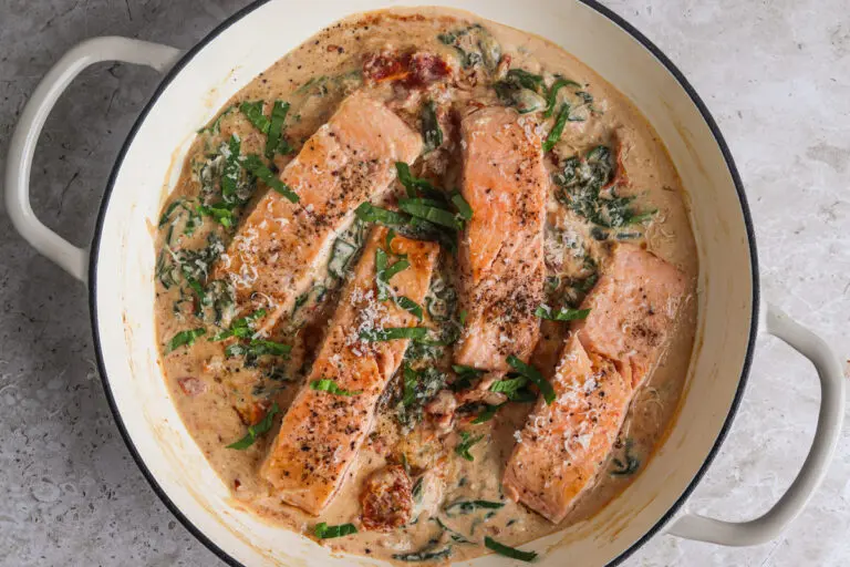 Creamy Tuscan Salmon cooking in one pan with spinach and sun-dried tomatoes.