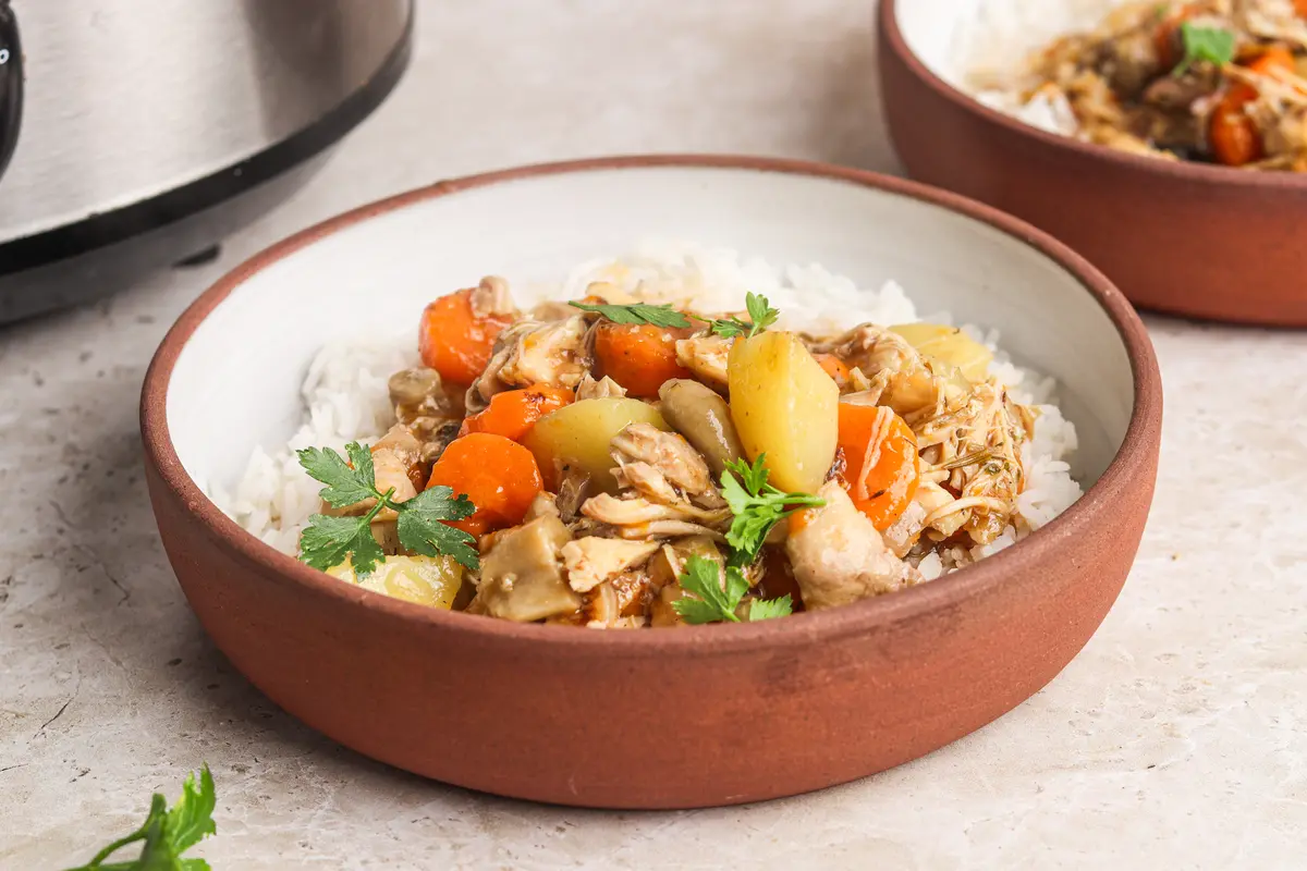 Chicken casserole served over rice in rustic bowl, garnished with fresh parsley