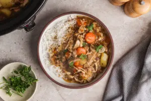 Top view of chicken casserole and rice in bowl with parsley and napkin on side