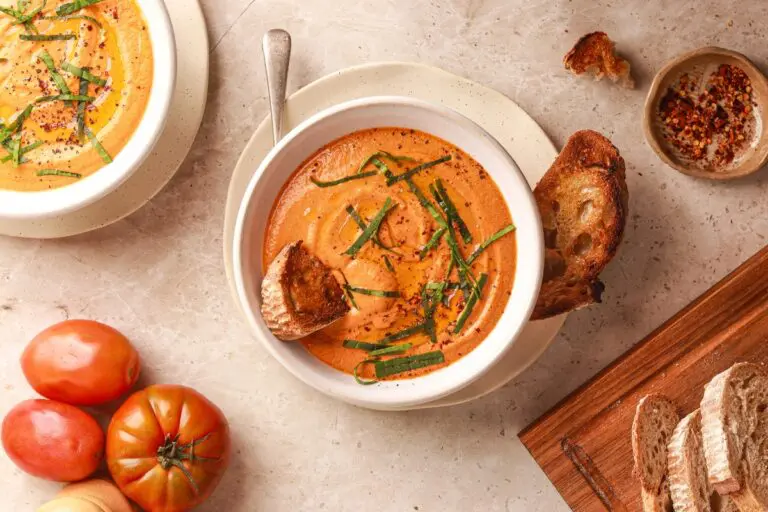 High protein tomato soup topped with basil and served with toasted sourdough