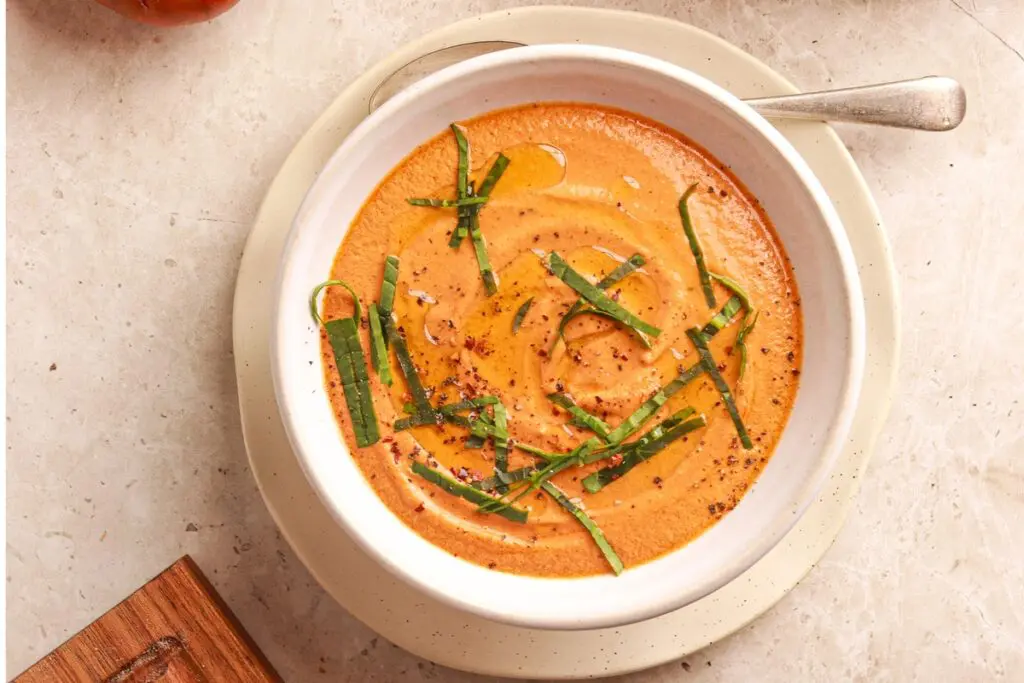 Creamy roasted high protein tomato soup with basil and olive oil drizzle.