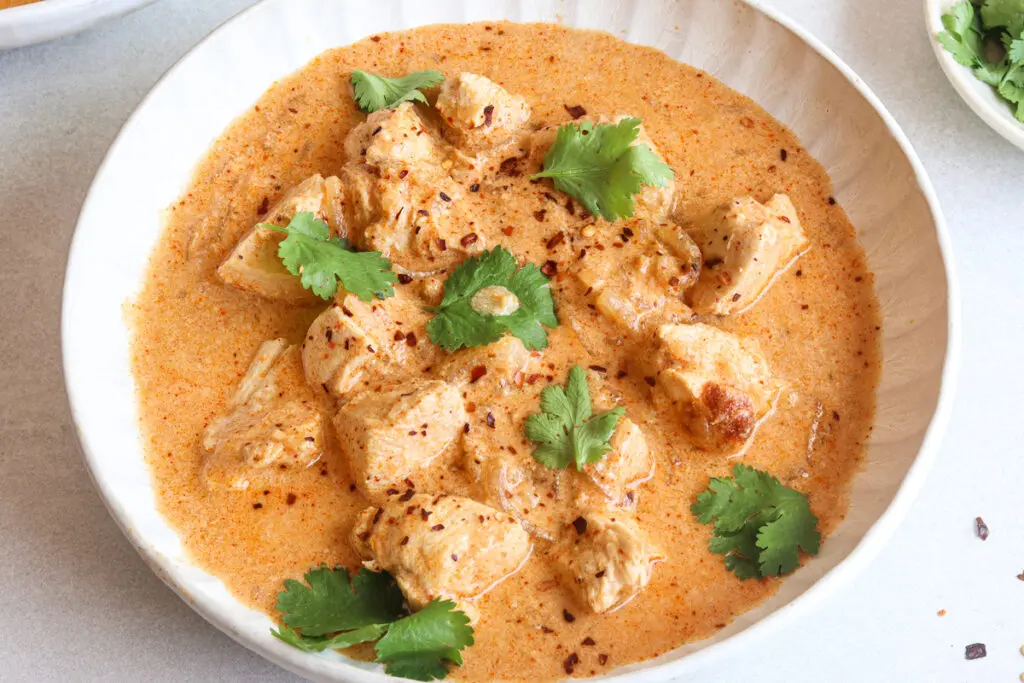 Slow cooker Thai red curry served with creamy coconut sauce and fresh herbs.