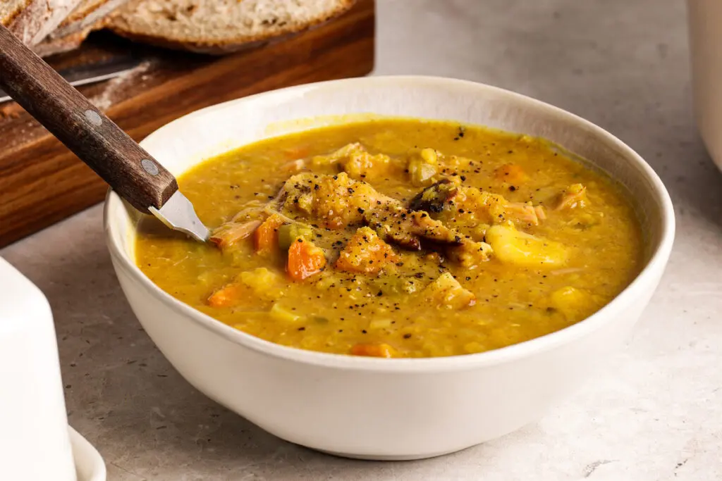 Bowl of Scottish lentil soup showing thick texture, ham hock and vegetables