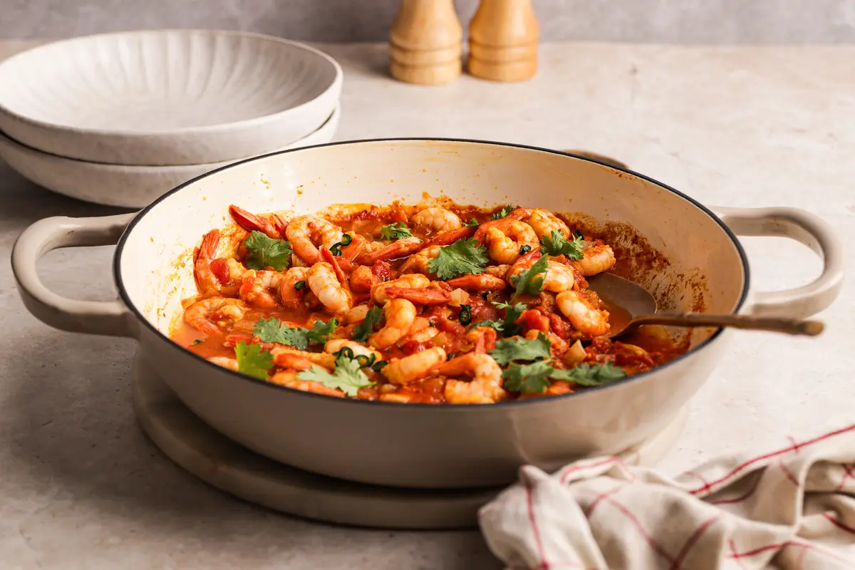 One-pan prawn curry in a shallow casserole dish, garnished with coriander and ready to serve.