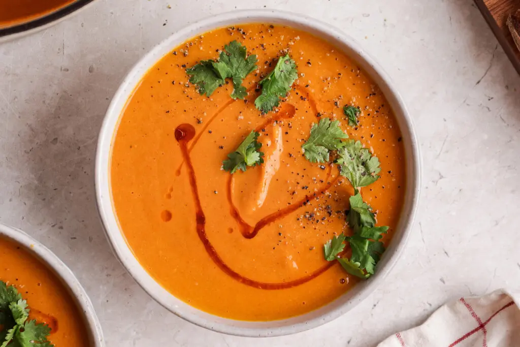 Close overhead shot of creamy sweet potato and chorizo soup with coriander and chilli oil