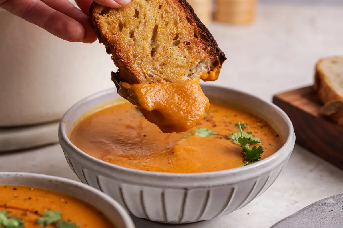 Close-up of bread lifting from sweet potato and chorizo soup with thick coating