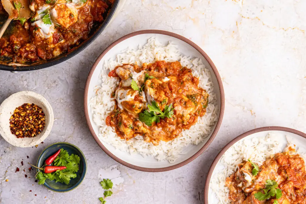 Chicken Karahi served over basmati rice with creamy yoghurt swirl, fresh coriander and chilli flakes