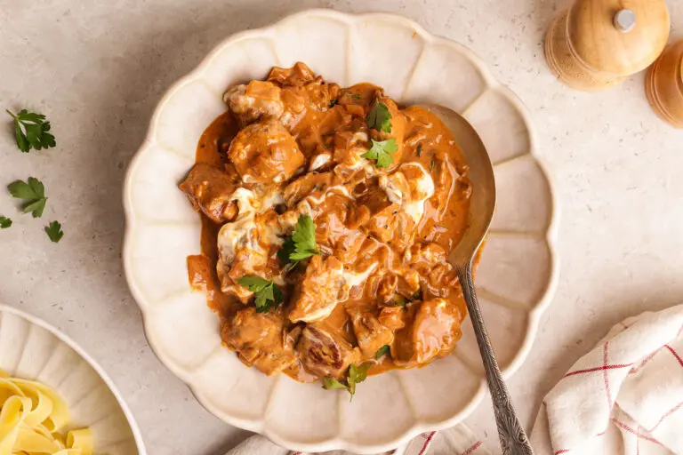 Creamy pork stroganoff with paprika sauce, tender pork fillet and parsley, served in a white bowl