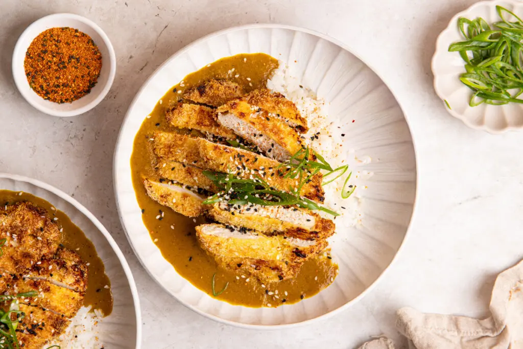 Crispy sliced chicken katsu on rice with smooth Japanese curry sauce and sesame garnish
