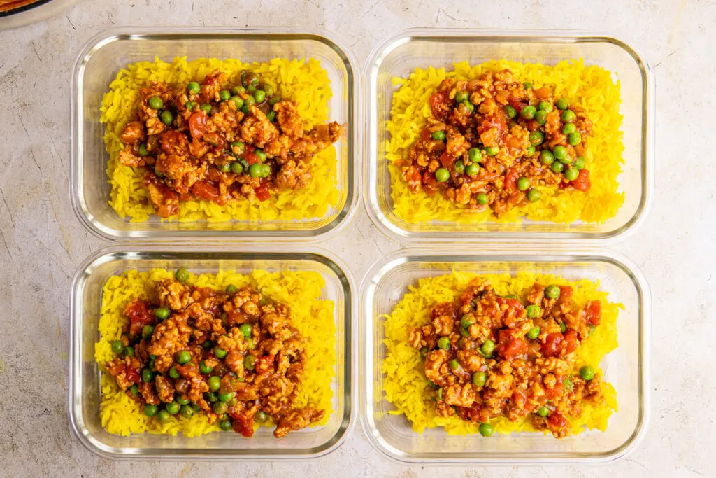 Meal prep containers with chicken keema served over yellow rice