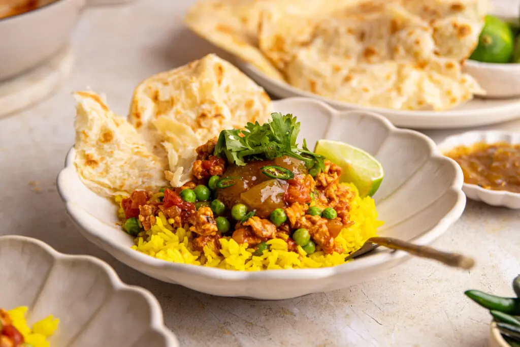 High-protein chicken keema with naan bread, lime wedge and coriander garnish
