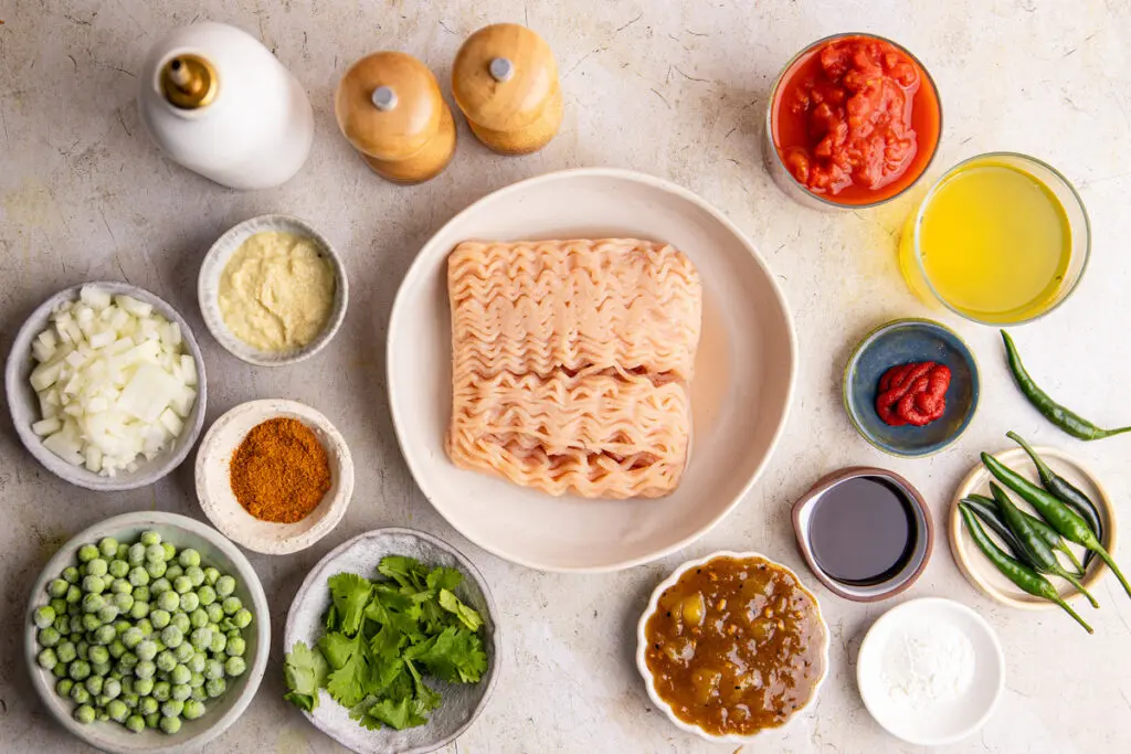 Flat lay of chicken keema ingredients including chicken mince, tomatoes, spices and herbs