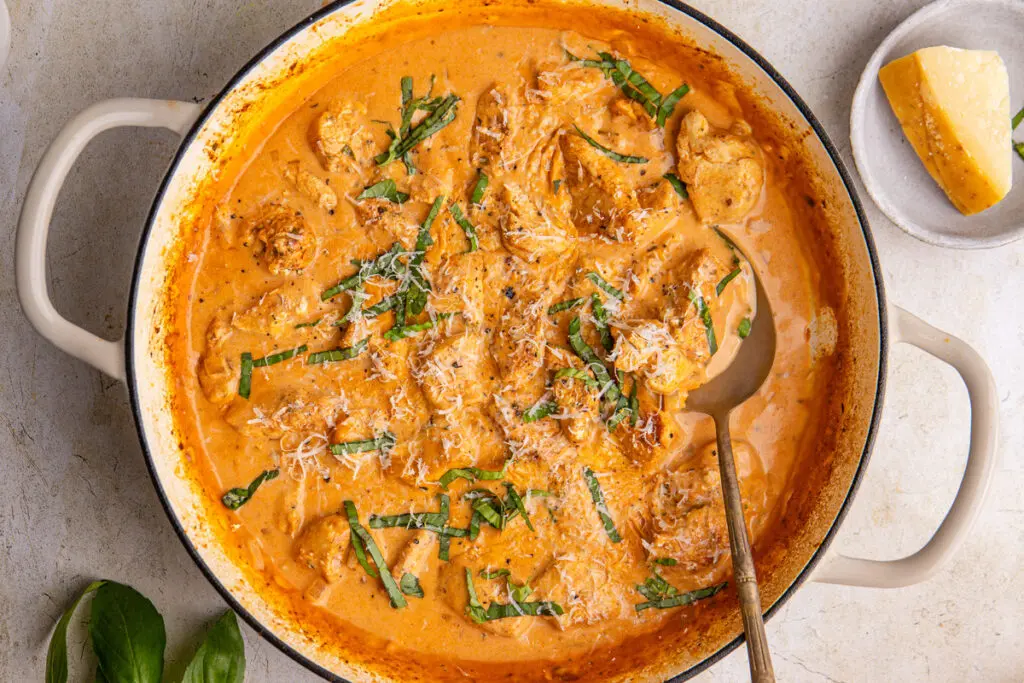 High-protein creamy paprika chicken in pan with parmesan and basil garnish