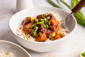 Close-up bowl of Diet Coke chicken coated in thick glossy sauce on fluffy rice