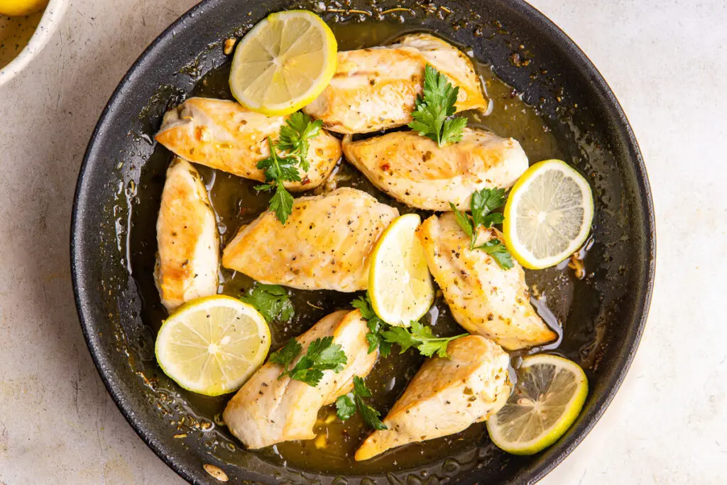 Pan-seared chicken breasts in glossy lemon sauce with parsley and lemon slices