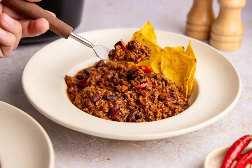 Fork lifting high-protein chilli con carne showing thick rich texture