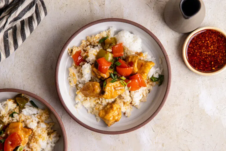 Bowl of sweet chilli chicken on rice with peppers and glossy sauce
