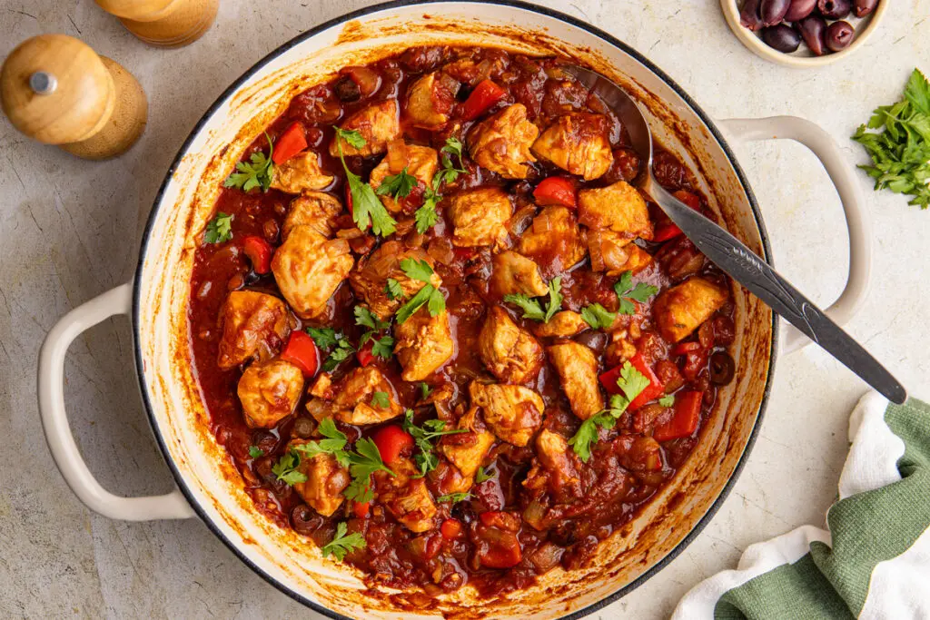 Brazilian chicken stew cooking in pan with chicken, peppers, olives and rich tomato sauce