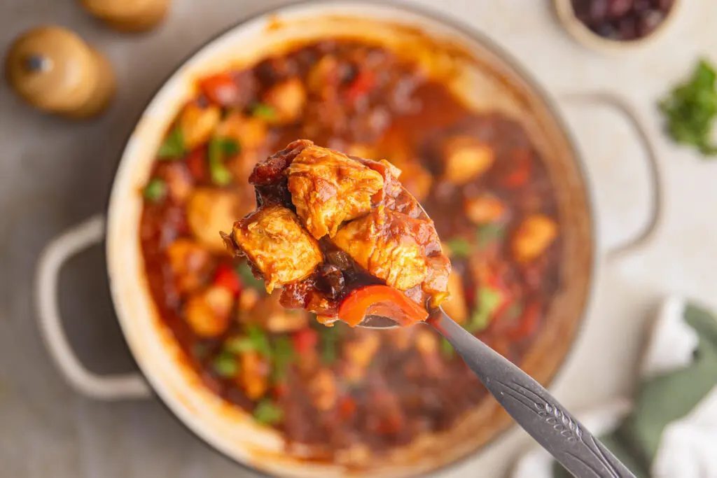 Close-up spoonful of Brazilian chicken stew with tender chicken, peppers and thick tomato sauce