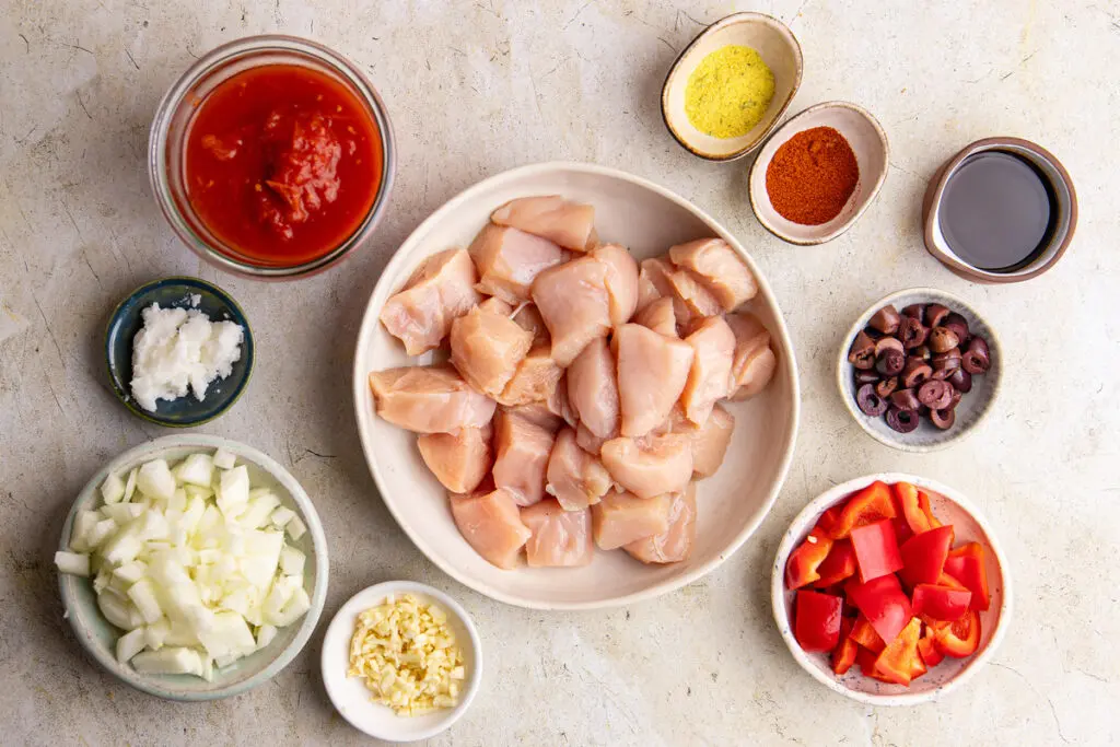 Raw ingredients for Brazilian chicken stew with chicken breast, peppers, onion, garlic, olives and spices