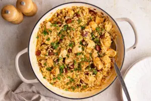Creamy high-protein chicken and chorizo risotto in a large pan, topped with fresh parsley and smoky crispy chorizo slices.