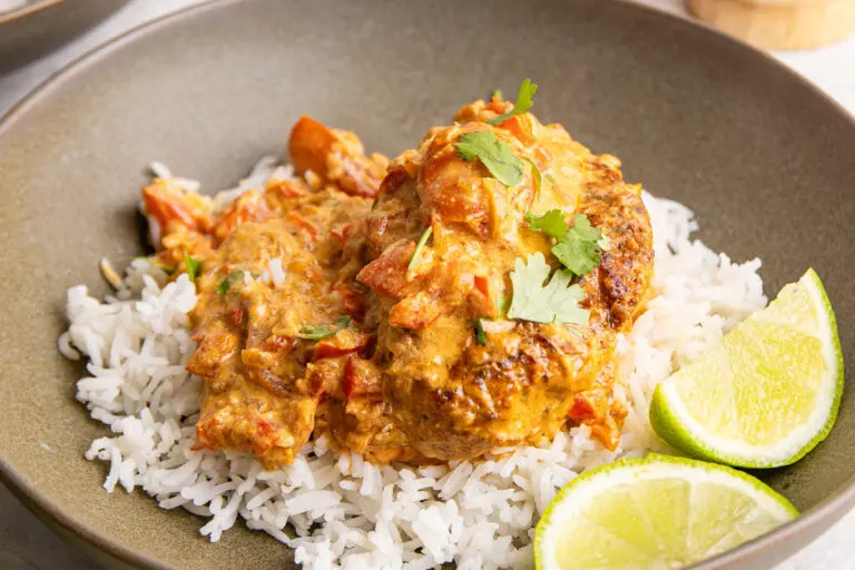 Creamy Cajun chicken breast with red pepper, tomatoes, lime and coriander on rice