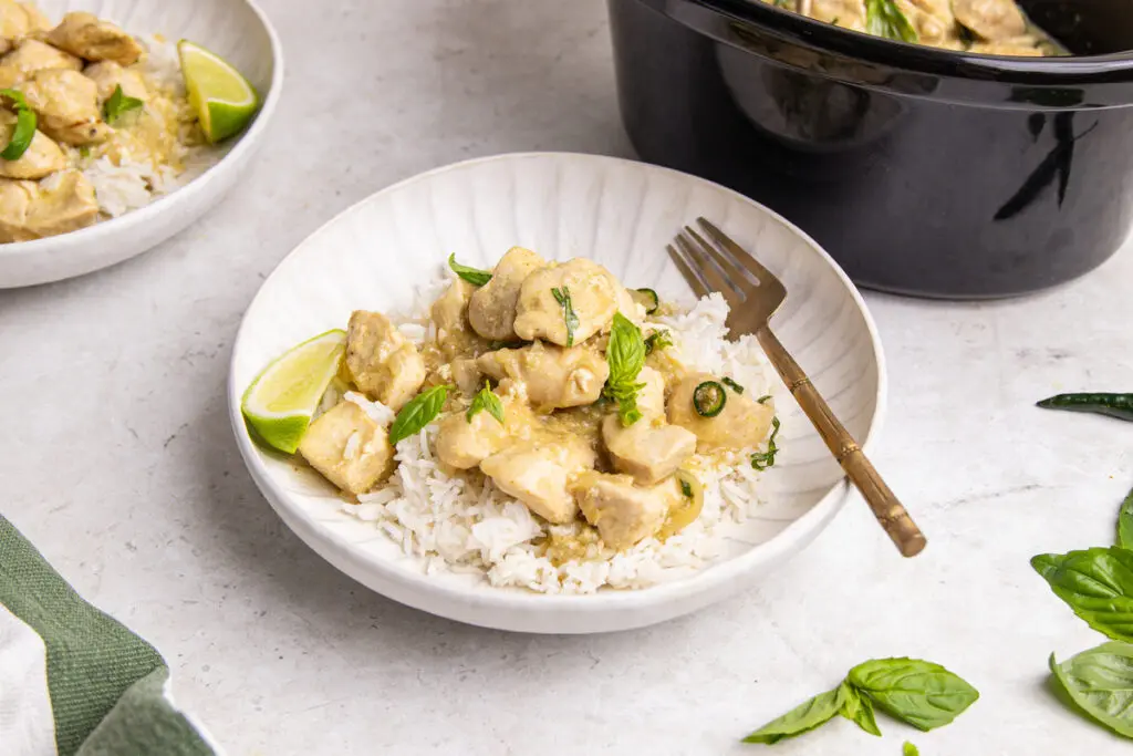 Slow cooker Thai green chicken curry served over rice with lime and basil garnish