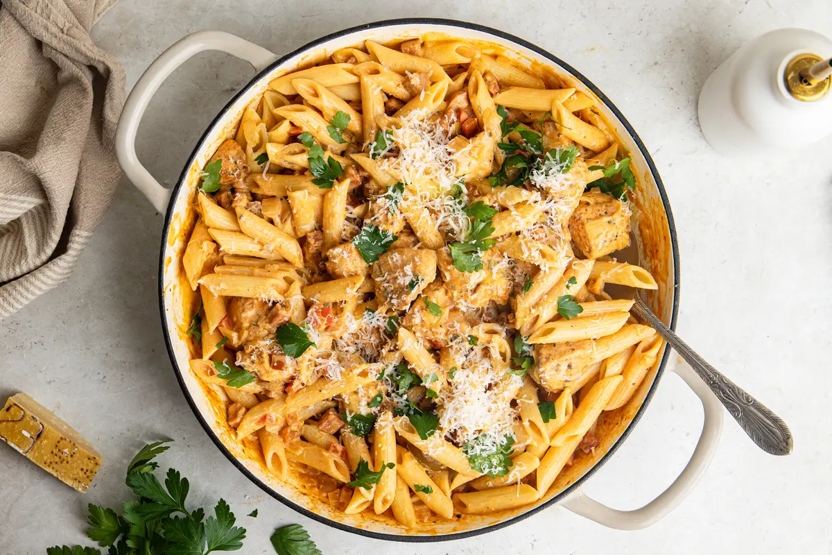 Overhead view of creamy chicken and chorizo pasta topped with Parmesan and fresh parsley.