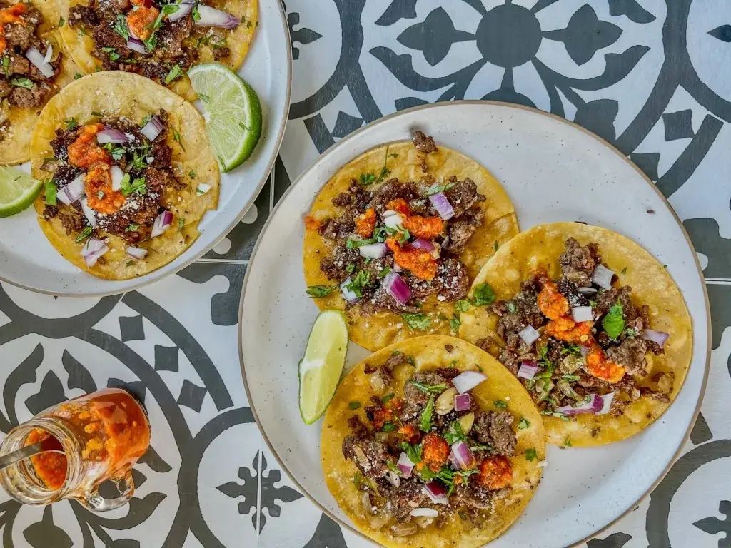 Crispy little tortillas piled with seasoned beef mince, red onion, coriander and punchy salsa make these tacos seriously hard to stop eating. A fun way to turn a slow cooker mince recipe into a build-your-own family dinner.